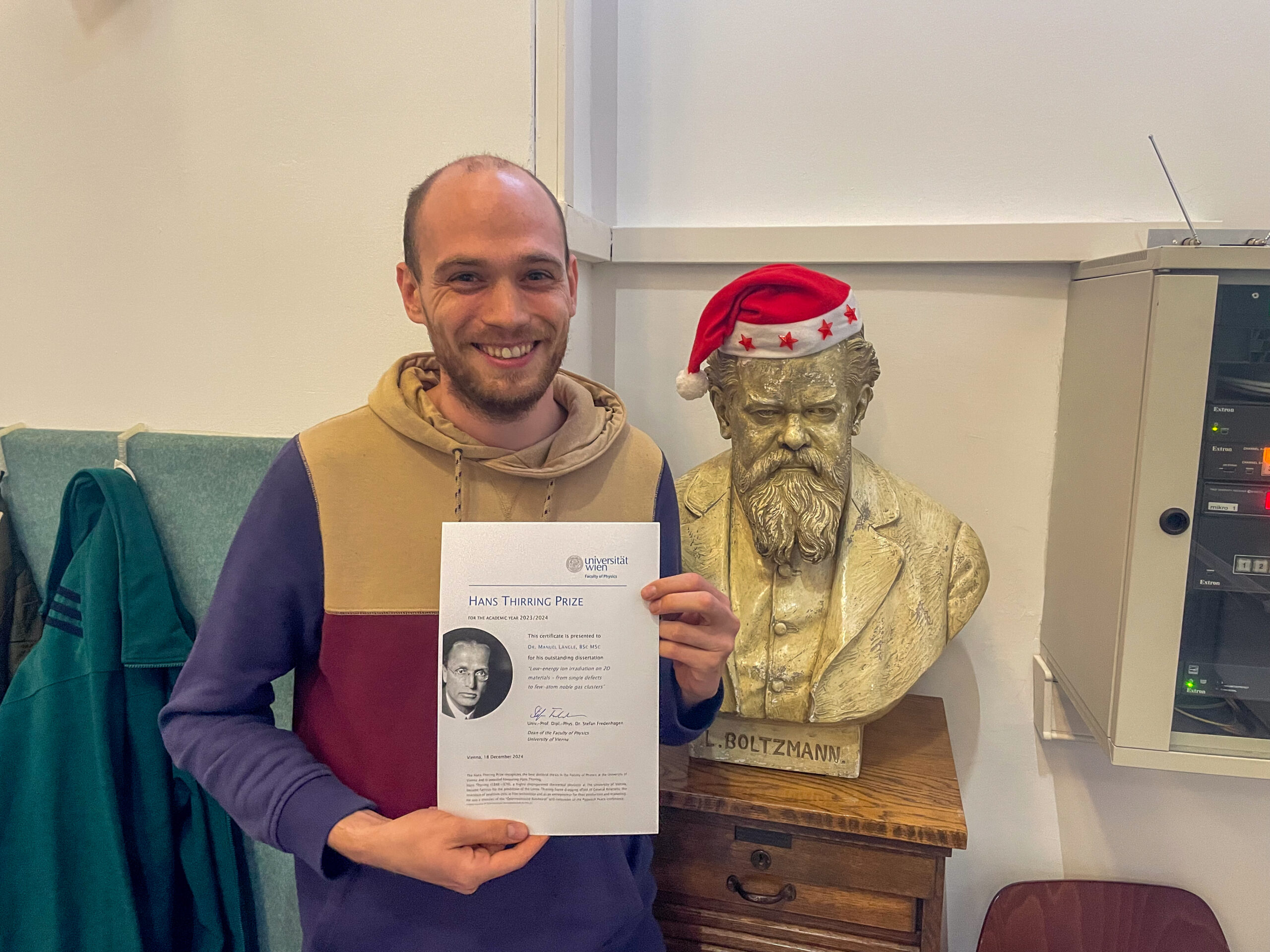 Manuel Längle next to a bust of Boltzmann with a Christmas hat